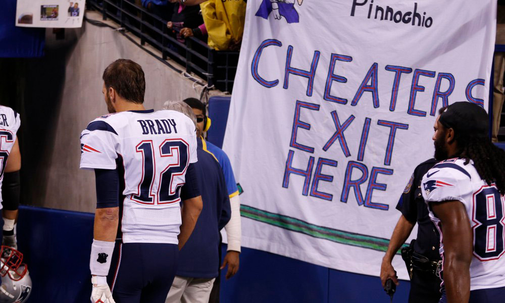 Oct 18, 2015; Indianapolis, IN, USA; New England Patriots quarterback Tom Brady (12) walks past a sign referencing Deflategate at halftime during the NFL game against the Indianapolis Colts at Lucas Oil Stadium. Mandatory Credit: Brian Spurlock-USA TODAY Sports